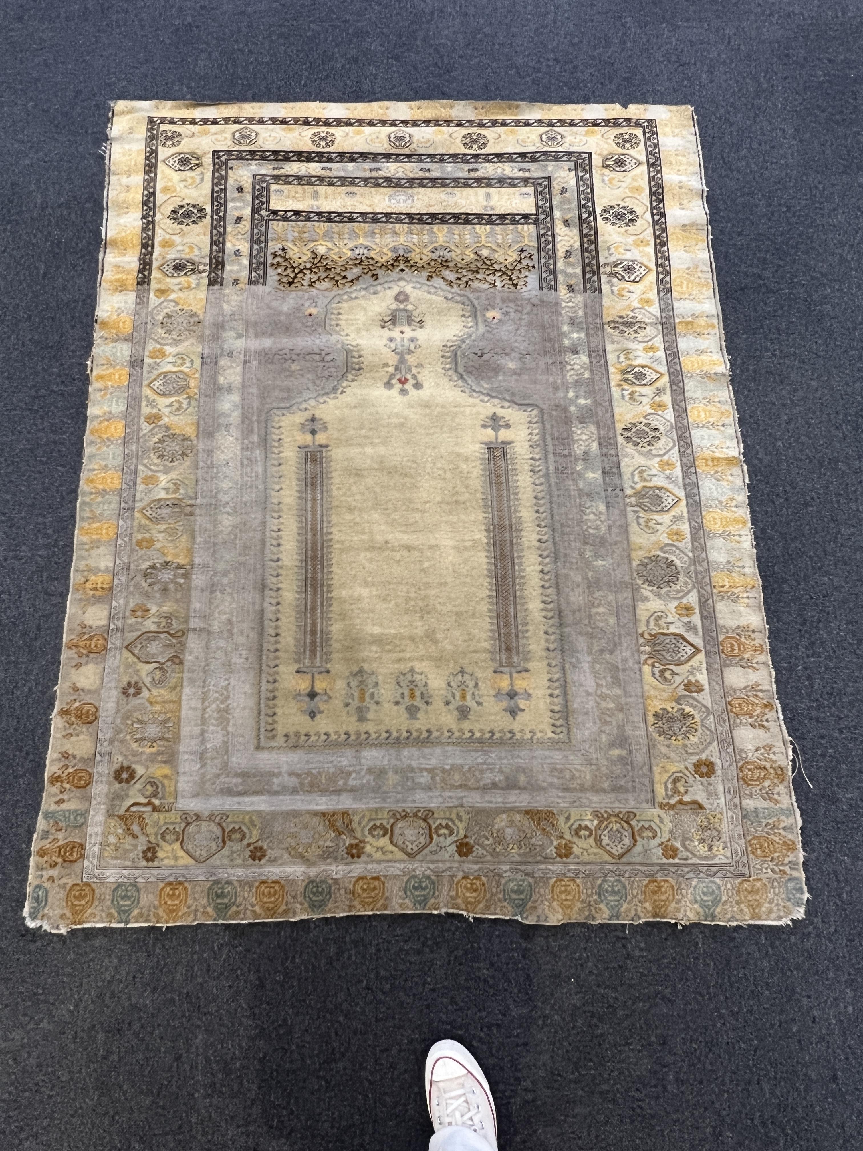 A Turkish silk prayer rug, with mihrab and stylised foliate borders on a gold ground, 185 x 137cm. Condition - the central panel severely worn to the tip of the mirror, lower fringe worn with losses.